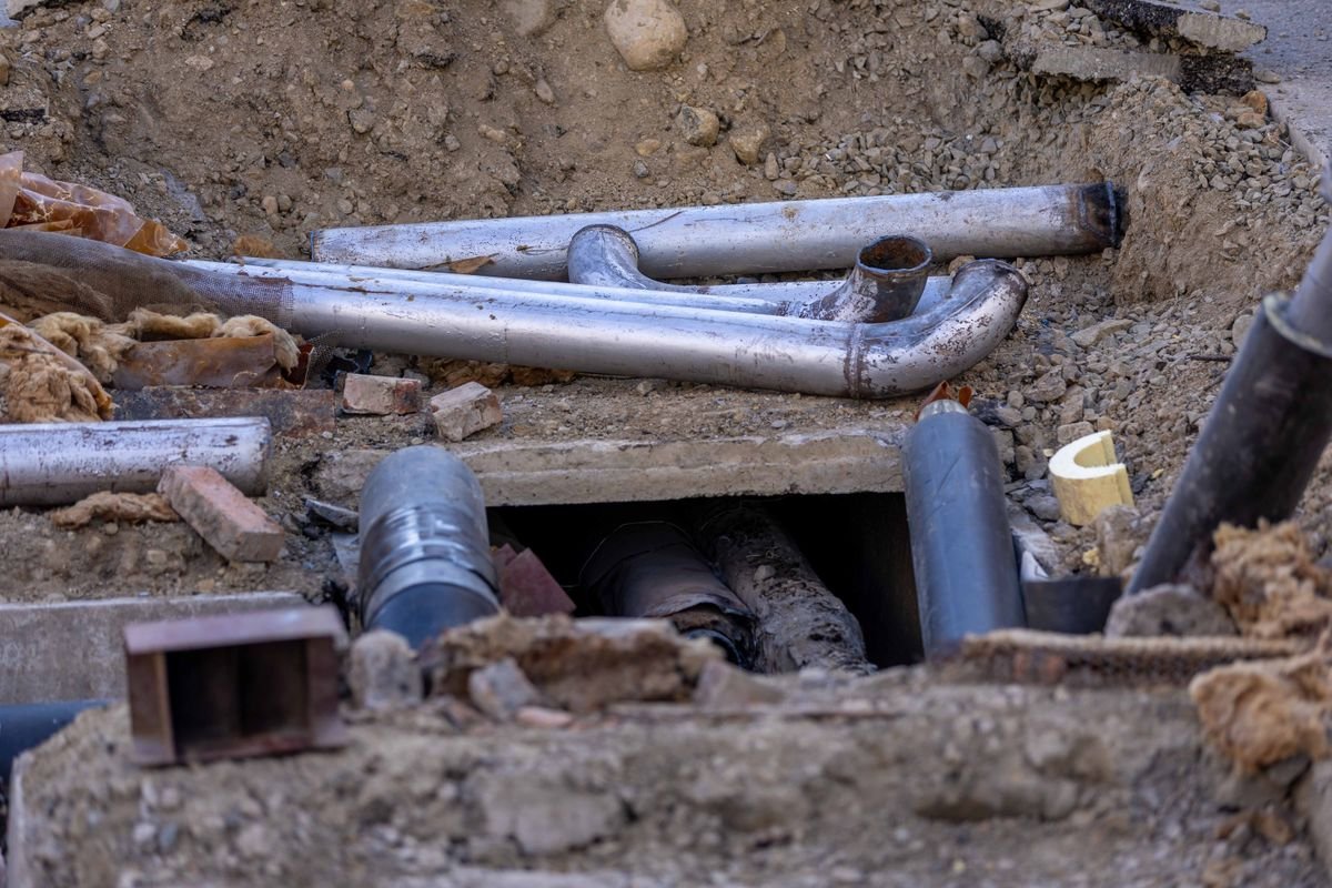 Exposed underground sewer pipes in an open trench during a repair job