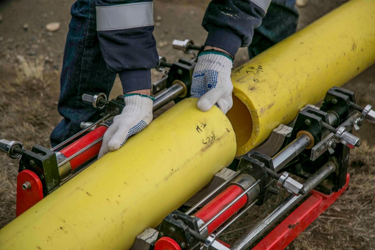 Worker joining a large-diameter pipe with installation equipment outdoors