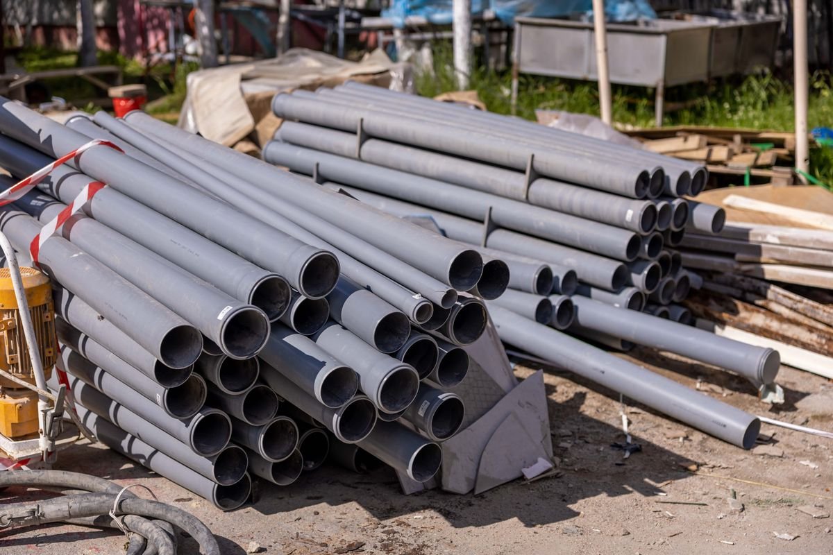 New grey PVC sewer pipes stacked at a work site, ready for installation